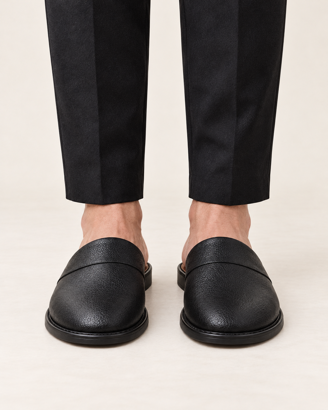 Men's black leather slippers, straight front view on feet